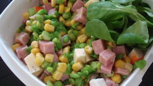 Une salade de maïs, avec du jambon, des petits pois et du surimi