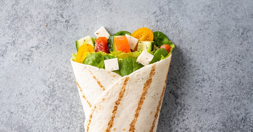 Wrap végétarien avec salade, tomates cerises, poivrons,
      fêta