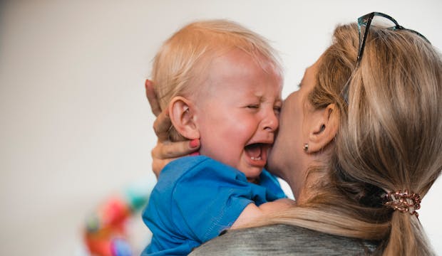 Bébé qui pleure dans les bras de sa maman.