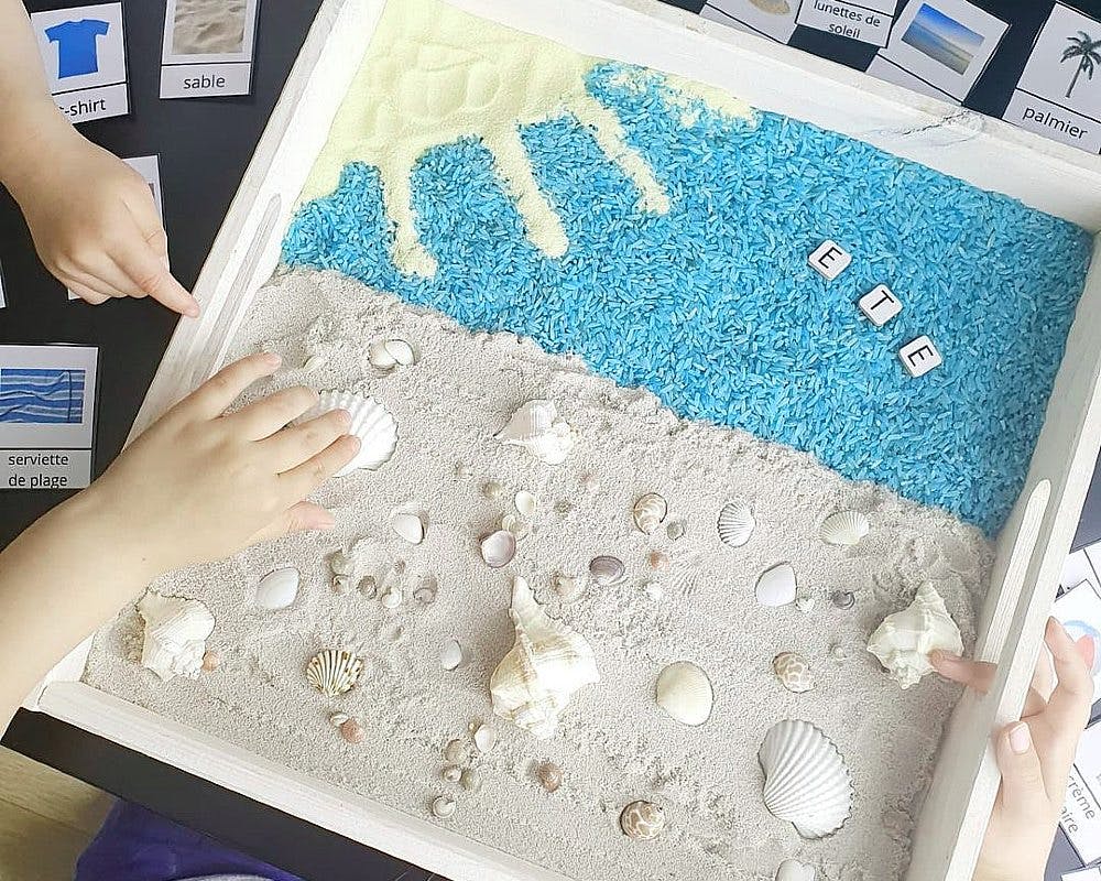 Un bac sensoriel composé avec du sable, du riz et des coquillages