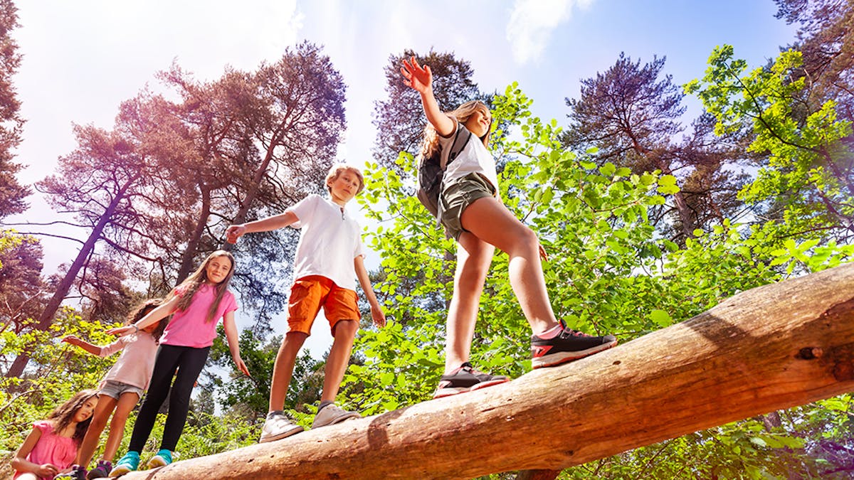 enfants qui marchent sur un tronc d'arbre