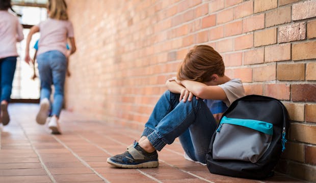 Jeune garçon accroupi dans un couloir d'école
